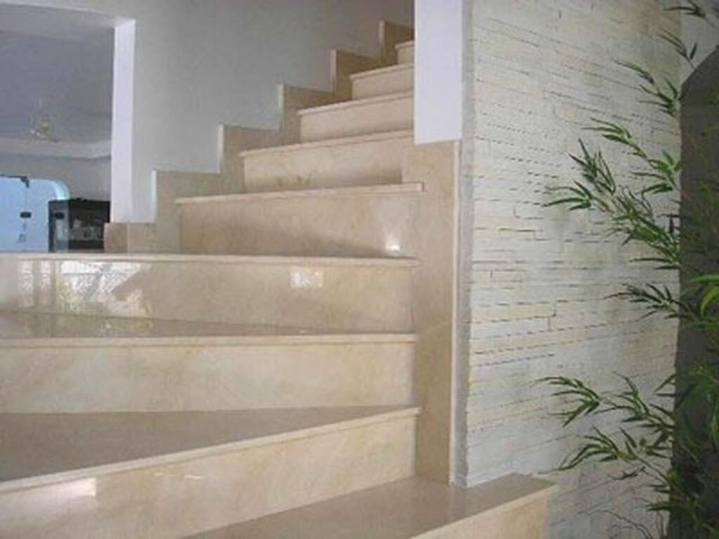 Escada em mármore creme com parede em revestimento de pedra